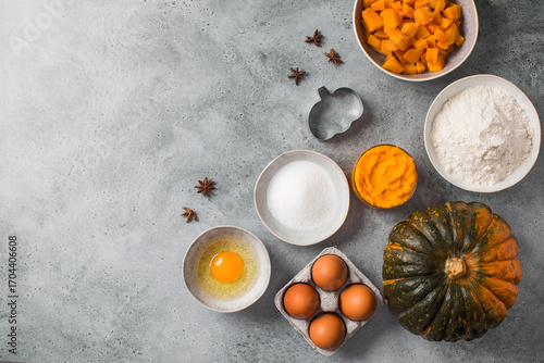 Baking ingredients for pumpkin pie prep on gray background. Autumn recipes. Copy space