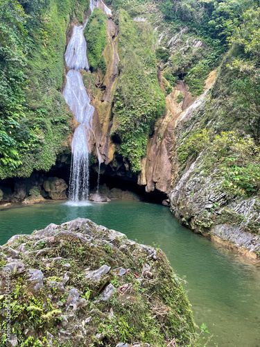 Waterfall cascading into the clear jungle pool surrounded by lush green forest in central Cuba, elevated view
