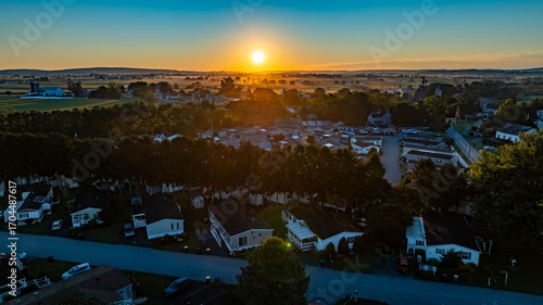Fotografie Golden sunlight breaks over rolling hills as it rises in the morning sky