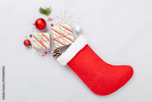 Christmas sock with gifts and decoration on color background, top view