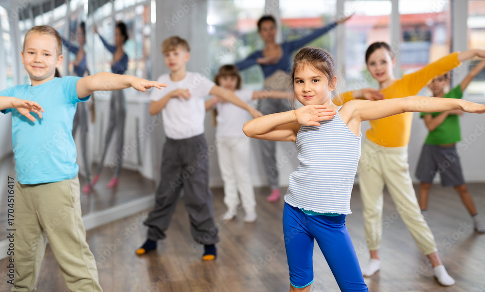Obraz premium Children studying modern style dances with female teacher in dance class indoors