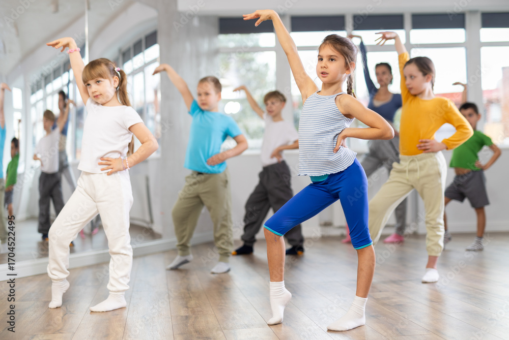 Fototapeta premium Children studying modern style dances with female teacher in dance class indoors