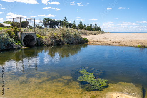Drain outlet with water flowing to sandy beach at Werribee South, Victoria, Australia. It carries water from inland areas (urban runoff, agricultural land, or stormwater) into the sea.