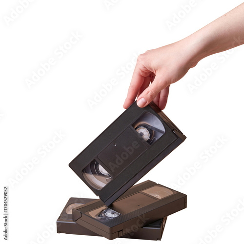 Hand holding a VHS tape above a stack of tapes