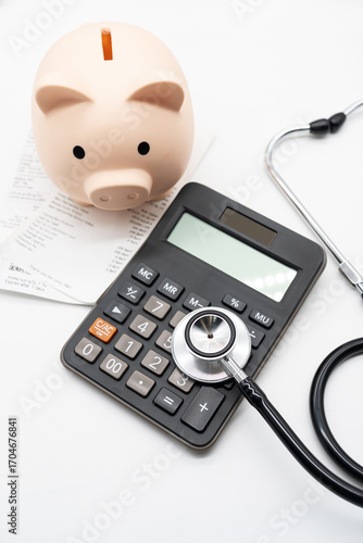 Piggy bank, calculator, and stethoscope with medical bills, symbolizing healthcare expenses, medical cost management, and financial planning. Health insurance, hospital billing, and medical cost.