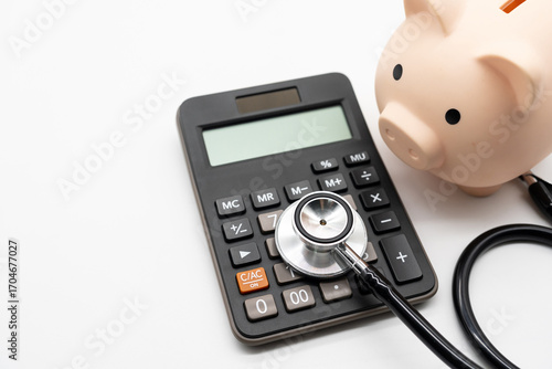 Calculator, Piggy bank and stethoscope on white background health medicine theme with copy space. Health care costs, medical cost management or medical insurance.
