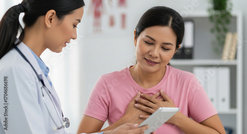 Asian female doctor explaining good test results to a patient on a tablet. Concept of medical care and positive news.
