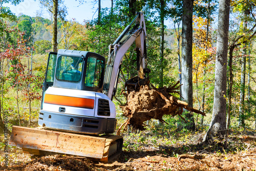 Excavator works on clearing tree roots debris in forest during works day.