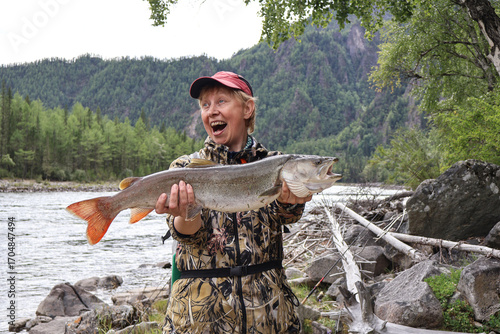 Unexpected passion: female angler celebrates taimen (Hucho taimen) fishing success