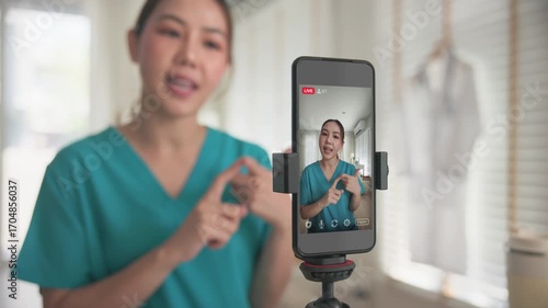Young adult woman asia Gen Z people anti aging expert modern nurse live talk viral video selfie camera on mobile phone app mental health care. Online sharing digital virtual asian vlogger filming.