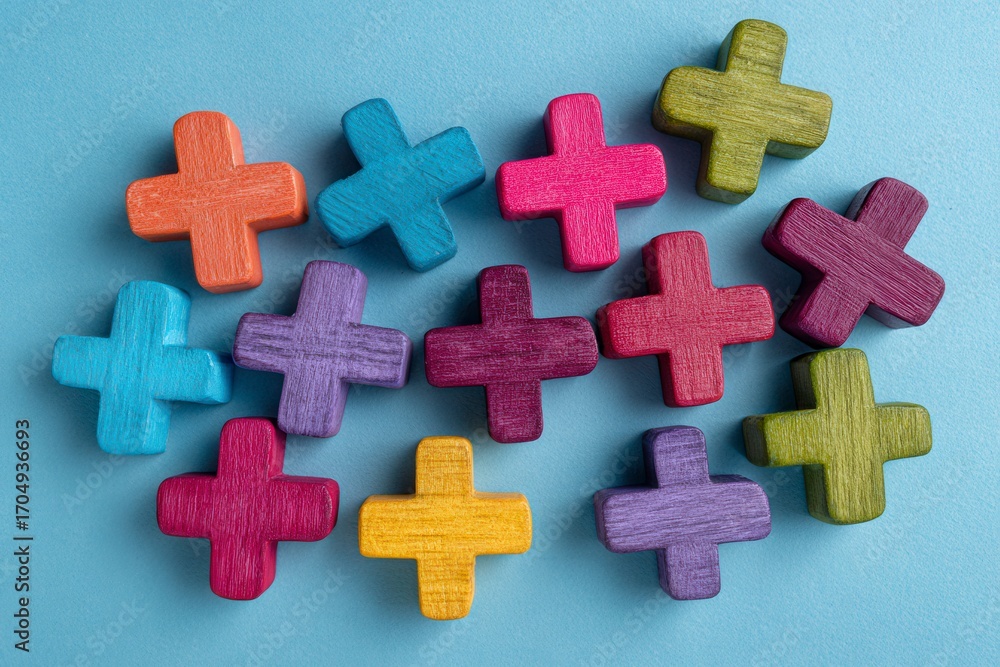 Obraz premium Colorful plus signs arranged on a light blue surface