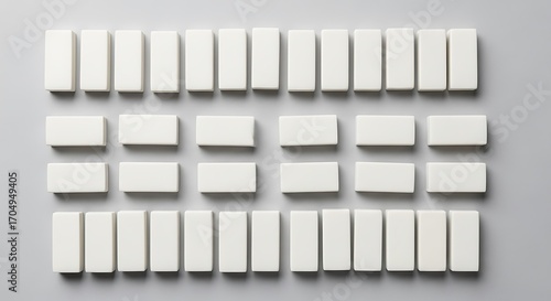 Minimalistic pattern arrangement of white erasers on a solid grey surface