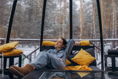 A woman is relaxing inside a domed tent at a glamping in the forest