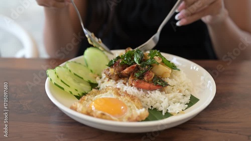 Wallpaper Mural Close-up of woman in restaurant eating Thai holy basil seafood dish with fried egg and rice during day Torontodigital.ca