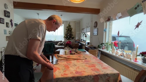 Latin American Traditions for Christmas and New Year in Europe A senior male cutting fabric with scissors, preparing an Año Viejo effigy, a Latin American tradition celebrating New Year's Eve