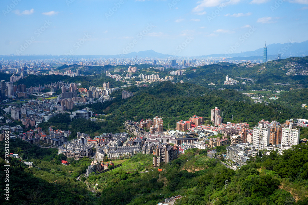 Fototapeta premium Expansive panoramic view of Taipei cityscape nestled within lush green mountains under a clear blue sky, highlighting a blend of urban development and natural beauty.