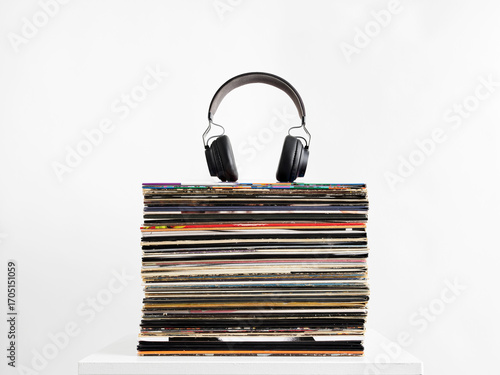 Headphones resting on stack of vinyl records representing music listening and collecting hobby