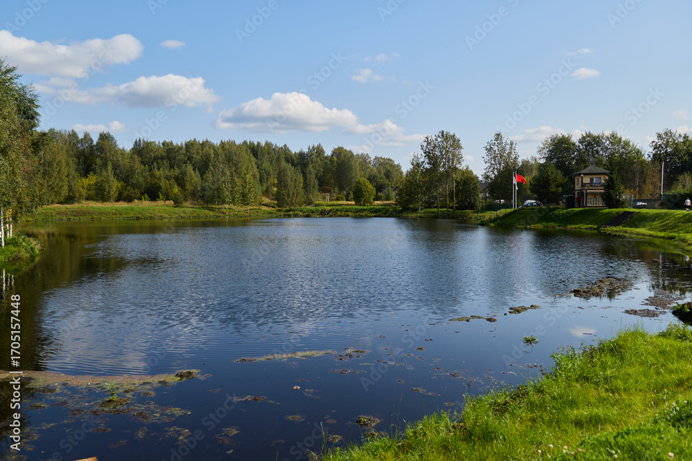 Obraz premium A Beautiful and Serene Lake Surrounded by Lush Greenery Under a Stunning Blue Sky Above