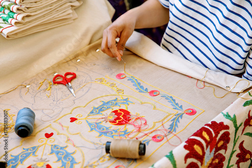 Papier peint In Tashkent, Uzbekistan, an artisan carefully hand-embroiders a vibrant floral pattern, surrounded by traditional Uzbek textiles