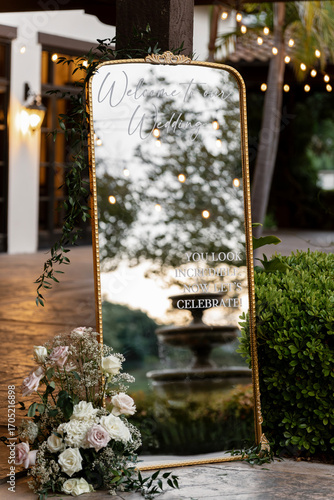 A mirror with the inscription Welcome to our wedding outdoors at the entrance to the banquet. An invitation on a floor mirror in a gold frame as a romantic and stylish detail of the wedding ceremony