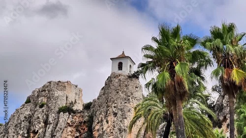 A picturesque, captivating temple located atop a rocky hill, surrounded by lush, vibrant palm trees and dramatic skies