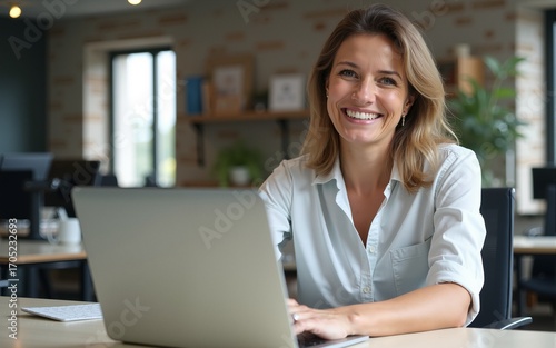 Happy cheerful mid aged business woman executive in office using laptop at work, smiling professional mature 40 years old female company manager working on computer at workplace. High quality