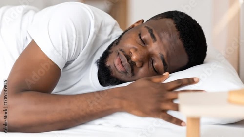 A man sleeps peacefully on a bed, expressing tranquility and relaxation, daytime sleep