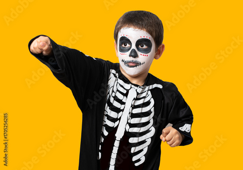 Quadro em tela Child dressed up as a skeleton fro Halloween trying to scare you with against an orange studio background