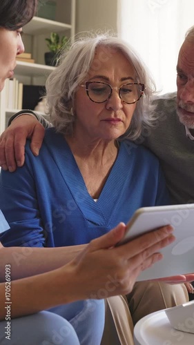 Senior woman receiving bad news on tablet with family support