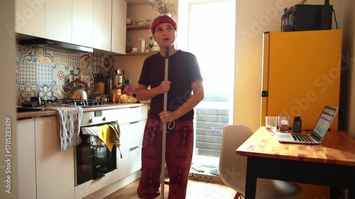 Creative Procrastination. A Hipster Woman Singing and Playing with a Broom. A Hipster Woman Dancing and Singing in a Modern Kitchen
