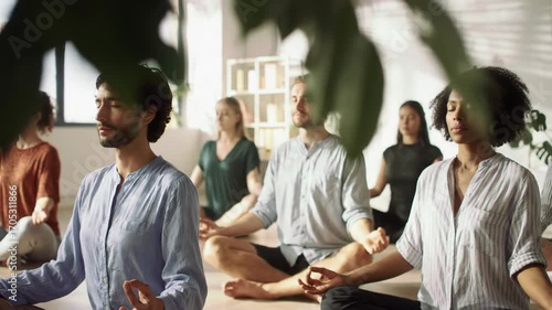 Group of diverse people meditating together indoors, yoga class for wellness and healthy lifestyle, mindfulness exercise for relaxation and stress relief.