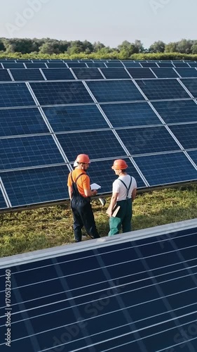 Engineers in hard hats inspect solar panels, promoting renewable energy and sustainability in a vertical video format.