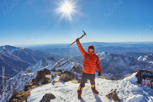 Alpinist standing at snow covered top of the peak of Jebel Toubkal in