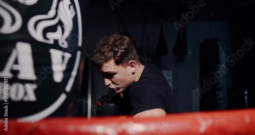 In a dim boxing ring, a determined man showcases his skills in an intense match