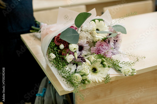 Bouquets brought as a gift to the teacher are on the desks of the students.