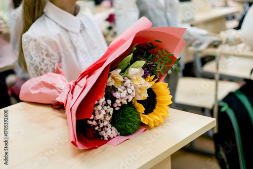 Bouquets brought as a gift to the teacher are on the desks of the students.