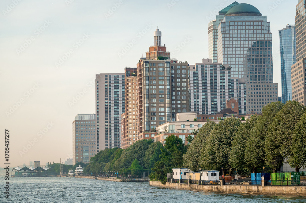 Obraz premium Buildings on the riverside in New York at sunset. Residential and office buildings in New York stand along the riverside under sunset light.