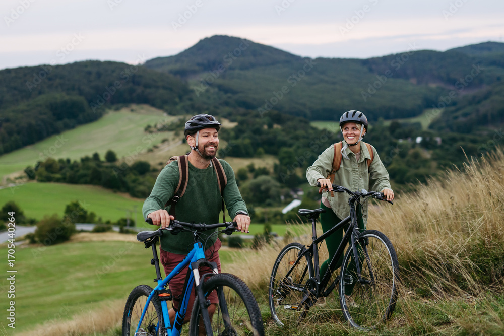 Fototapeta premium Couple cycling together in nature, smiling and enjoying outdoor adventure.