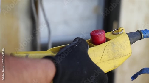 Close-up of a worker pressing a hoist control button to lift structural elements during construction.