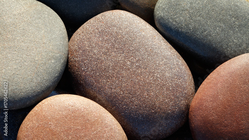 Photography Pebbles round stones on the sea beach are illuminated by the morning sun and have warm sunny shades as a textured SPA background for page design template
