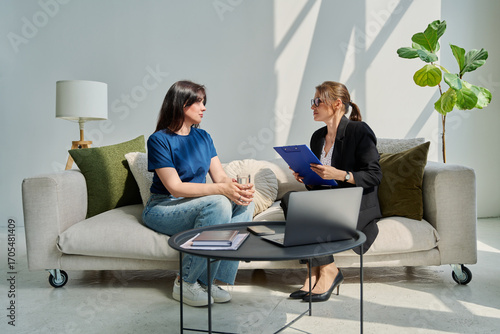 Female patient talking to psychotherapist psychologist, sitting together in office