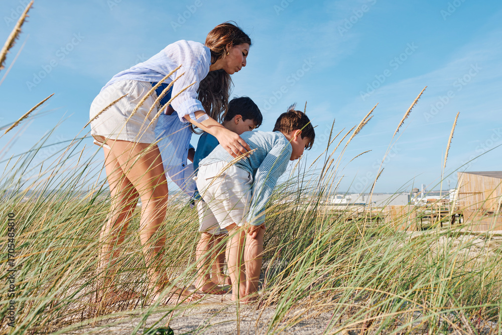Mother and children looking at grass at beach Mother and children looking at grass at beach
