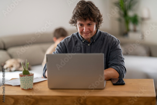 Man smiling at Laptop in a Bright Home Office