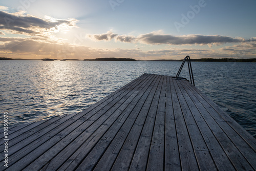 Fototapeta Naklejka Na Ścianę i Meble -  Amazing golden sunset over the Turku archipelago in south east Finland with a view on a typical swimming jetty which are everywhere on the many islands for locals to enjoy the Balic sea after a sauna