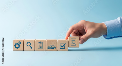 A hand places a wooden block with a checklist icon, completing a row of business process symbols.