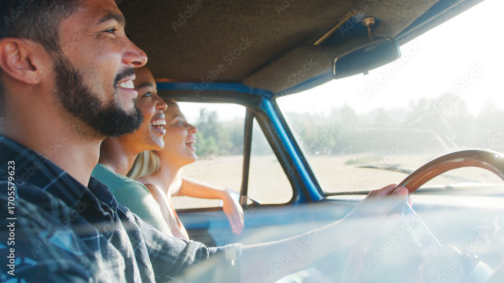 Naklejka premium Group Of Friends Sitting In Cab Of Pick Up Truck On Road Trip Through Countryside