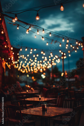 Magical evening atmosphere with glowing string lights illuminating an outdoor dining area at dusk