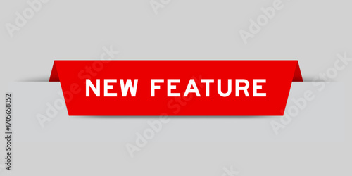 Red color inserted label with word new feature on gray background