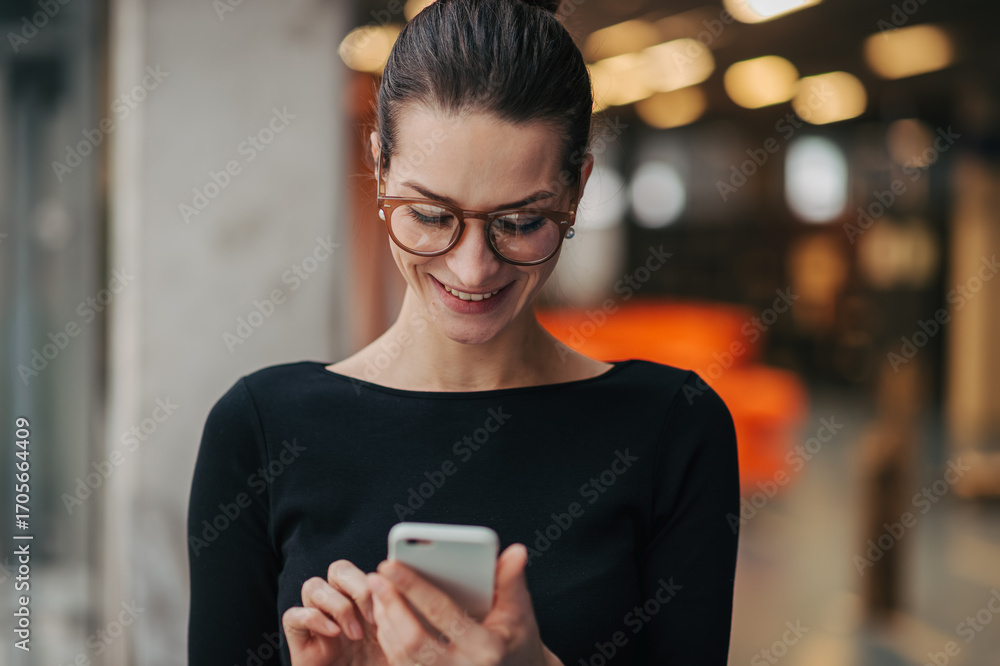 Fototapeta premium Portrait of young businesswoman reading email on smartphone.