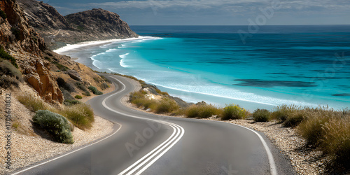 Winding coastal road with dashed white lines stretching into the distance, beside an empty beach and calm turquoise sea.